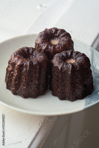 Caneles de bordeaux - traditional French sweet dessert. Canele on round white plate