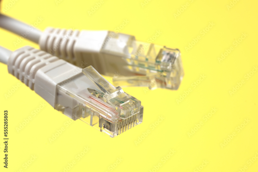Network connection, internet connection and computer technology concept, close-up of ethernet cable connector, on yellow background Network connection, internet connection and computer technology concept, close-up of ethernet cable connector, on yellow background