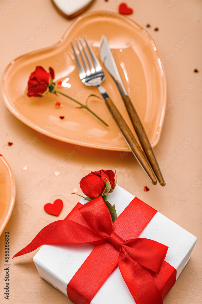 Table setting for Valentine's Day with gift, roses and hearts on beige background, closeup Table setting for Valentine's Day with gift, roses and hearts on beige background, closeup