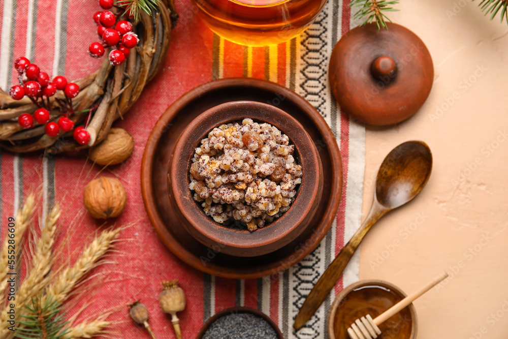 Pot of Kutya with ingredients and Christmas wreath on beige background