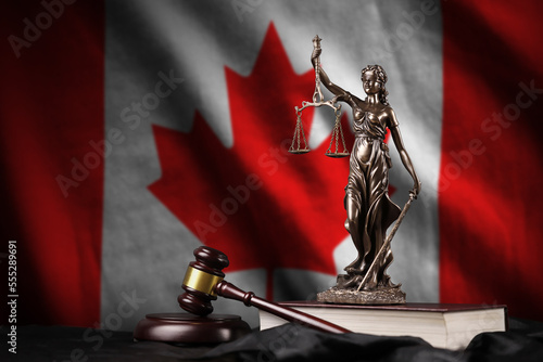 Canada flag with statue of lady justice, constitution and judge hammer on black drapery. Concept of judgement and punishment