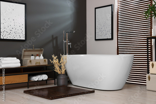 Stylish bathroom interior with ceramic tub  towels and cosmetic products