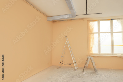 Room with pale orange walls and windows prepared for renovation