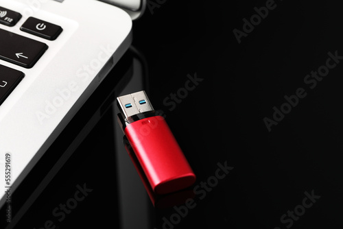 Modern usb flash drive near laptop on black table