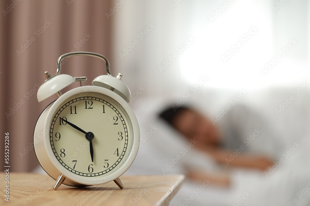 Woman sleeping in bedroom, focus on alarm clock. Space for text Woman sleeping in bedroom, focus on alarm clock. Space for text
