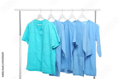 Turquoise and light blue medical uniforms on rack against white background