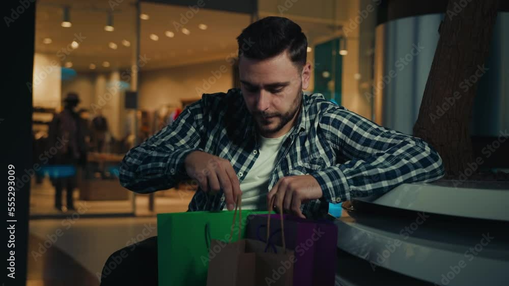 Male shopaholic businessman customer client caucasian man unpacking bags with presents buying luxurious gifts on Black Friday sales receiving delivery packages supermarket purchases in shopping mall Male shopaholic businessman customer client caucasian man unpacking bags with presents buying luxurious gifts on Black Friday sales receiving delivery packages supermarket purchases in shopping mall