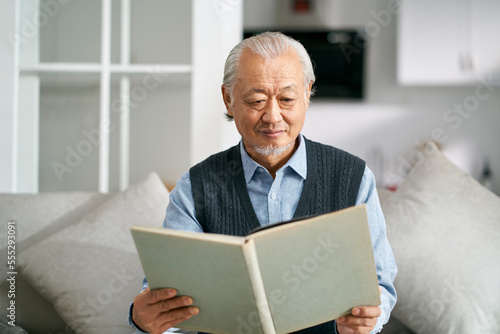 senior asian man reading a book at home