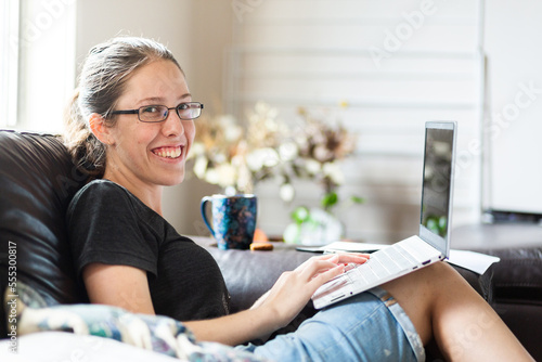 Young woman in her twenties working from home on laptop on lounge photo