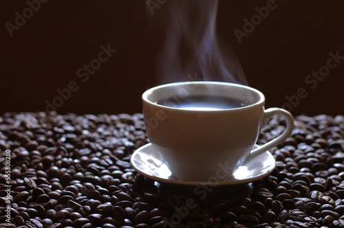 A cup of coffee with steam smoke on a wooden table.