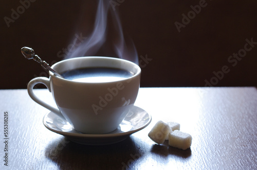 A cup of coffee with steam smoke on a wooden table.