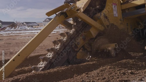 Close up slow motion of dirt flying on construction site from trencher photo
