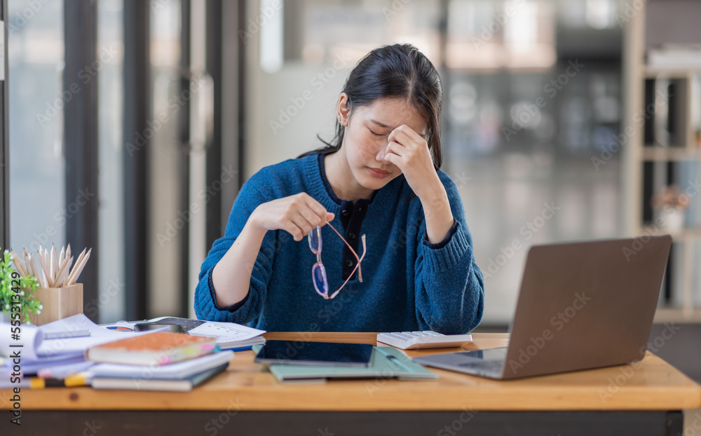 Portrait of tired young business Asian woman work with documents tax laptop computer in office. Sad, unhappy, Worried, Depression, or employee life stress concept. Portrait of tired young business Asian woman work with documents tax laptop computer in office. Sad, unhappy, Worried, Depression, or employee life stress concept.