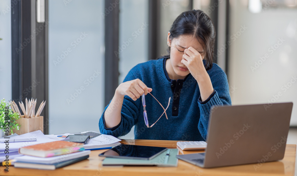 Portrait of tired young business Asian woman work with documents tax laptop computer in office. Sad, unhappy, Worried, Depression, or employee life stress concept. Portrait of tired young business Asian woman work with documents tax laptop computer in office. Sad, unhappy, Worried, Depression, or employee life stress concept.