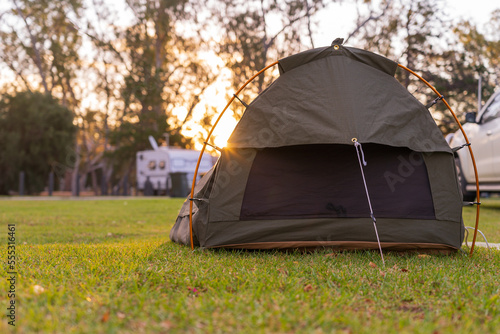 Low angle view on a sleeping swag set up on a grassy area of a campground at sunset photo