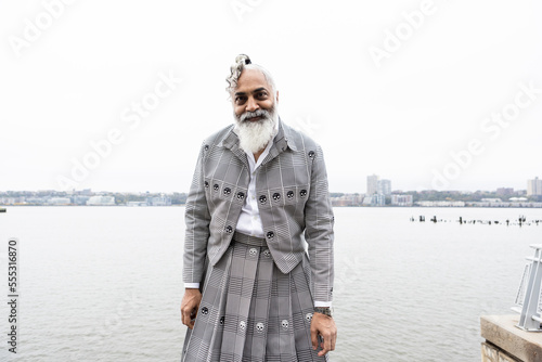 man with gray hair and beard wearing skirt suit with city view