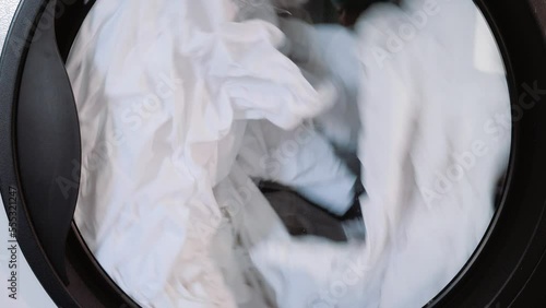 Laundry. a white sheet spins in the washing machine drum. close-up