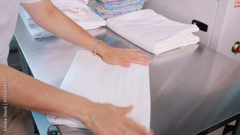 Women's hands stack white bed linen. Dry cleaning Women's hands stack white bed linen. Dry cleaning