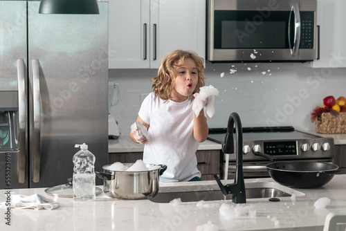 Obraz na plátně Child washing dishes near sink in kitchen
