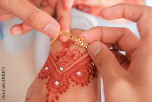 The groom put the wedding bracelet to the bride during solemnization ceremony. Family and happiness concept.