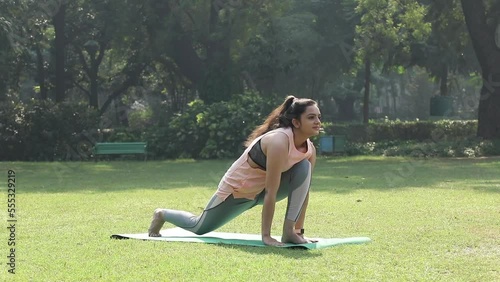 Video of an Indian woman doing the Surya Namaskar in a park.