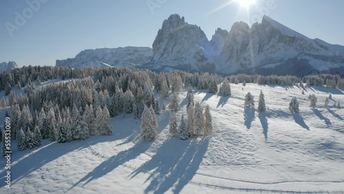 4k drone flight moving to the side footage of Alpe di Siusi ski resort with Plattkofel peak on background. Sunny morning scene of Dolomite Alps. Winter in Ityaly, Europe. Ultra High Definition... photo