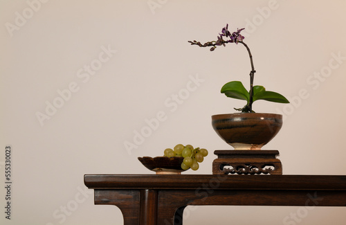 Purple orchid, Chinese antique ceramic and White grapes on wooden table against white wall © WeeKwong