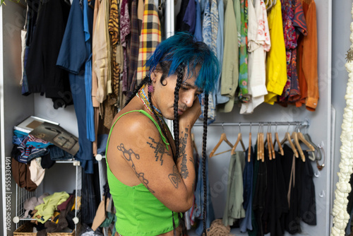 indigenous non-binary artist with blue hair getting dressed