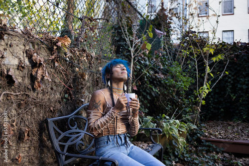 Foto indigenous non-binary artist drinking tea in urban garden in autumn