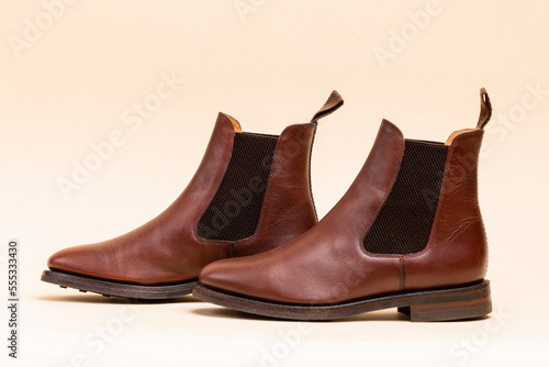 Footwear ideas. Closeup of Pair of Classic Leather Chealsea Boots As Still Life Concepts Placed Close to One Another Over Beige Background.