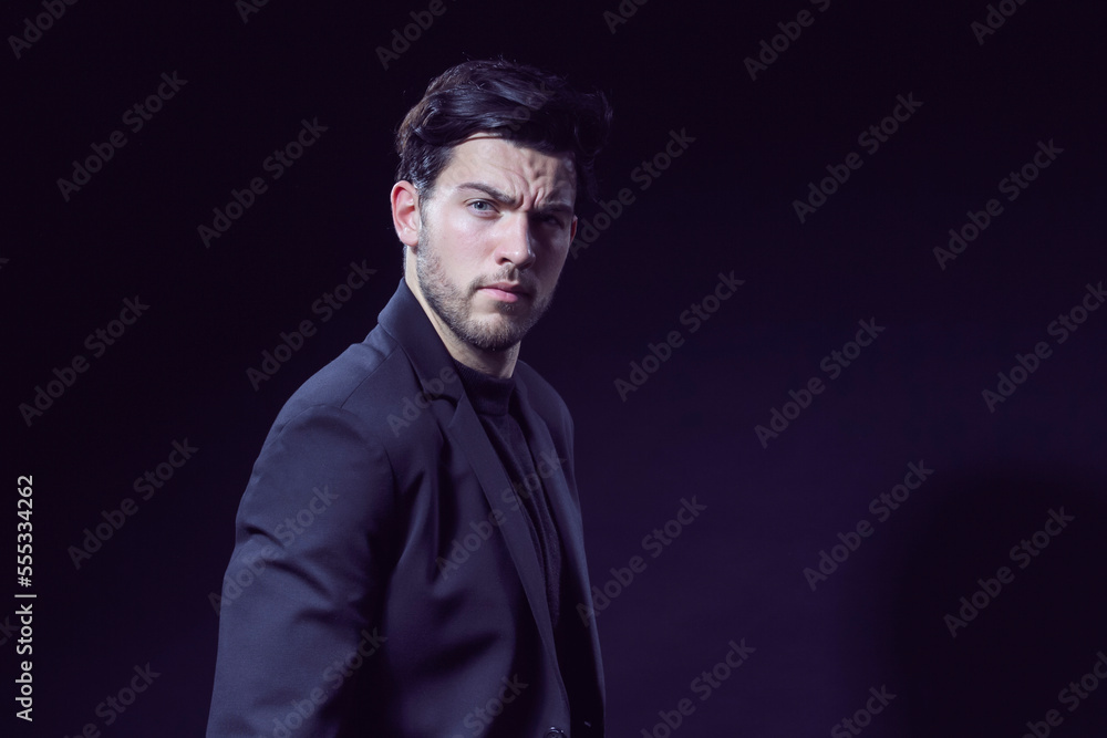 One Handsome Caucasian Brunet Businessman Wearing Black Suit Posing With Folded Hands Looking Aside Against Black