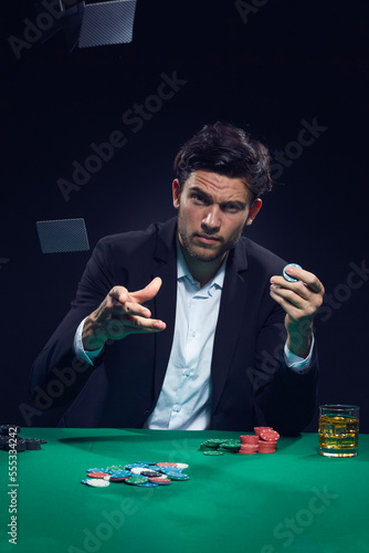 Gambling Concepts. One Emotional Handsome Caucasian Brunet Cards Player At Pocker Table With Chips Flying and Cards While Playing