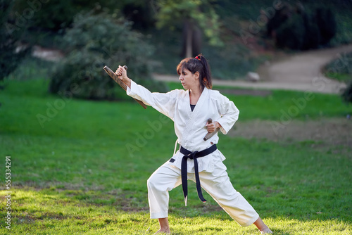 Karate fighter woman in white kimono and black belt training outdoors. Sports and martial arts concept.