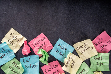 New year goals or resolutions on bright colorful paper stickers. New Year goals List 2023, plan listing of new year beginnings goals and resolutions setting. Flat lay copy space on black background