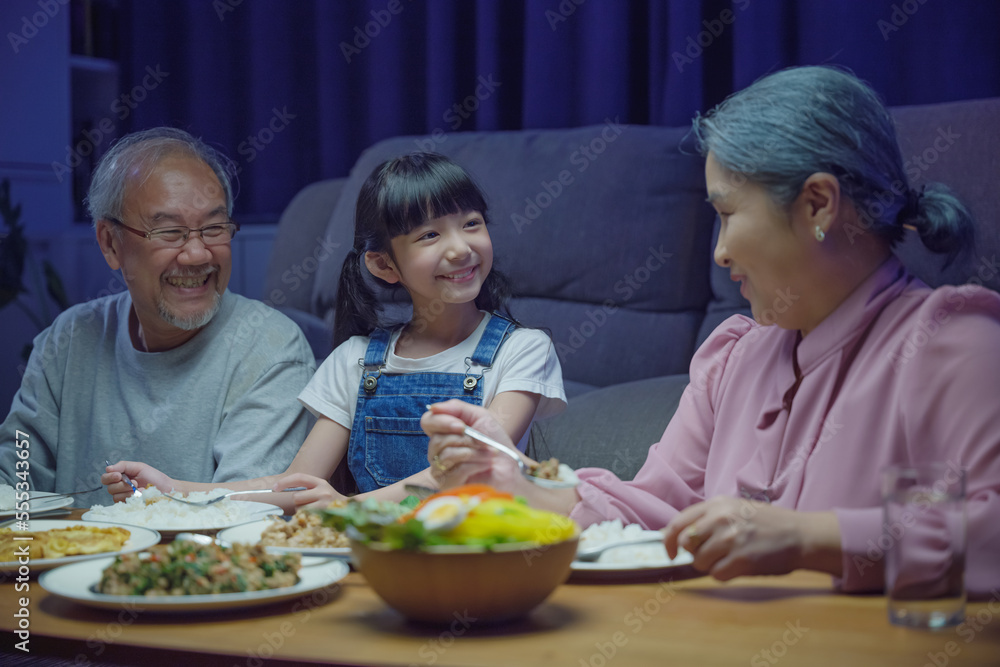 Happy Asian senior parent and child eating dinner food together in
