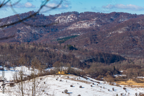 Fototapeta Naklejka Na Ścianę i Meble -  panorama of krywe village in polish bieszczady mountains by the san river; old destroyed orthodox church on the hill in snowy winter weather