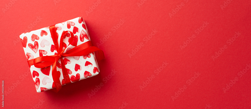 Valentine's Day concept. Top view photo of giftbox in wrapping paper with heart pattern on isolated red background with copyspace Valentine's Day concept. Top view photo of giftbox in wrapping paper with heart pattern on isolated red background with copyspace