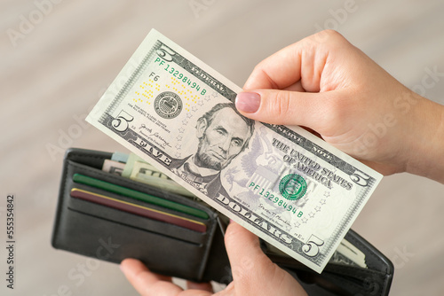 Close up shot of five dollar banknote in hands on a woman. American money, finances, payments concept