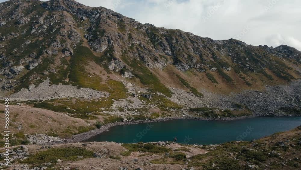 Young woman hiking glacier lake top of mountain, aerial wide shot Young woman hiking glacier lake top of mountain, aerial wide shot