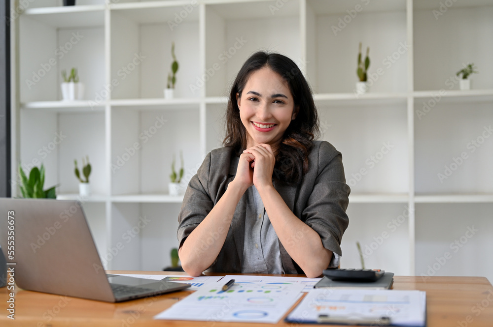 Charming Asian businesswoman sits at her desk putting her hands together, smiling Charming Asian businesswoman sits at her desk putting her hands together, smiling