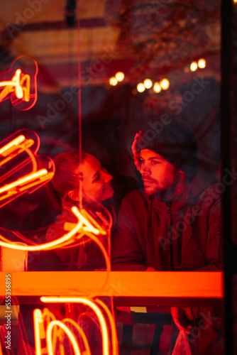Outdoors Valentines Day Date Ideas for Couples. Winter love story. Cold season dating for couples. Young couple in love in neon lights in evening night winter city street