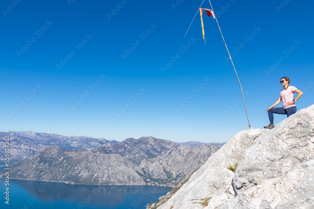 Obraz premium Woman with panoramic view from Derinski Vrh of Kotor bay in sunny summer, Adriatic Mediterranean Sea, Montenegro, Balkan Peninsula, Europe. Fjord winding along coastal towns. Lovcen, Orjen mountains