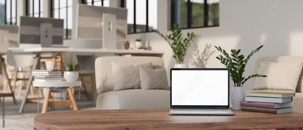 Laptop mockup and decor on coffee table over blurred background of modern office workplace Laptop mockup and decor on coffee table over blurred background of modern office workplace