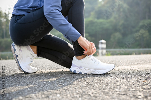 cropped, A woman in sportswear tying her running shoes, preparing to run on the street.