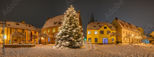 Panorama view of market square with decorated Christmas tree covered with snow on winter day.  Christmas atmosphere at the town hall market of Schleswig, Schleswig-Holstein, Germany.