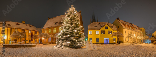 Panorama view of market square with decorated Christmas tree covered with snow on winter day.  Christmas atmosphere at the town hall market of Schleswig, Schleswig-Holstein, Germany. photo