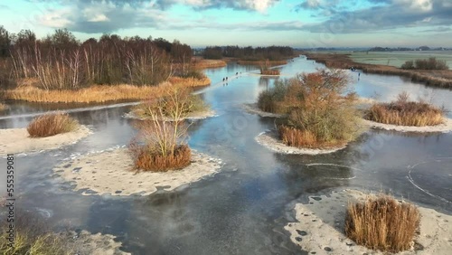 Ice skating on the Drontermeer lake in nature seen from above during a cold winter day in The Netherlands. photo