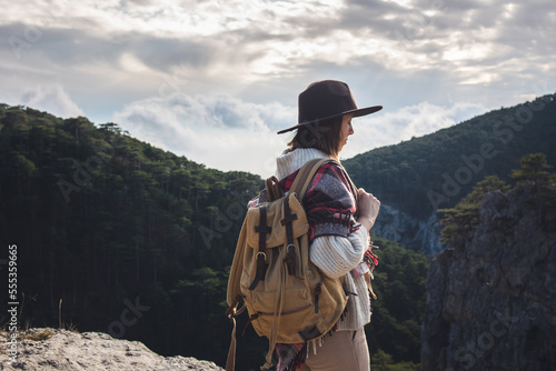 Hiker woman with backpack enjoying mountain view alone outdoors. Travel and outdoor activities, healthy lifestyle. Beautiful view of the mountains.