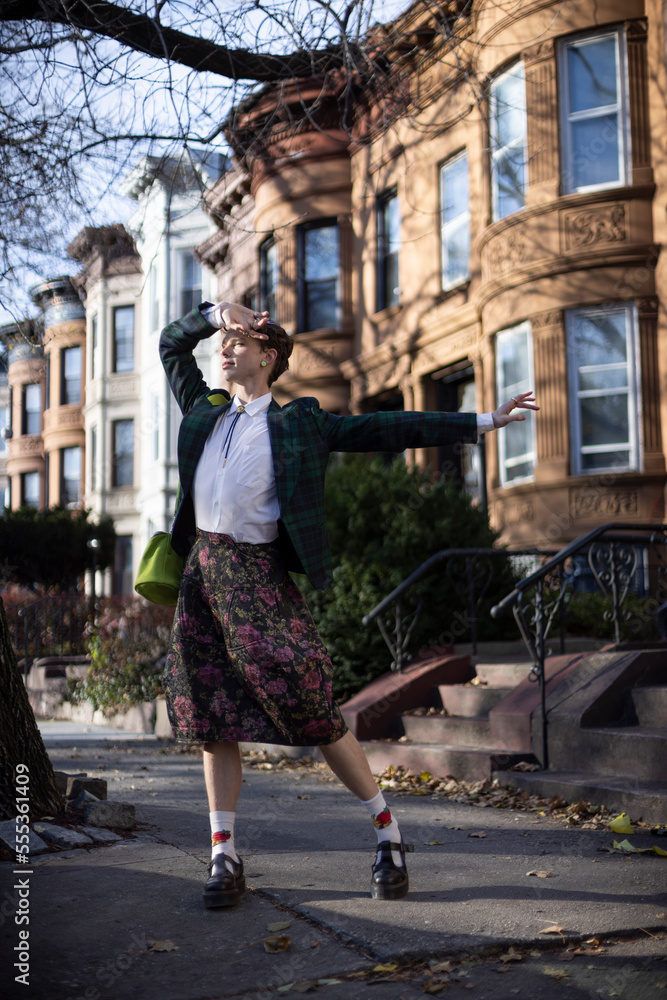 non-binary caucasian person with short hair dancing on Brooklyn sidewalk