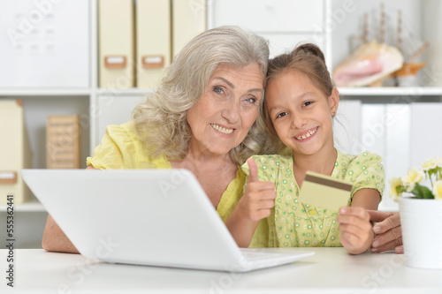 Happy grandmother and granddaughter using laptop shopping online